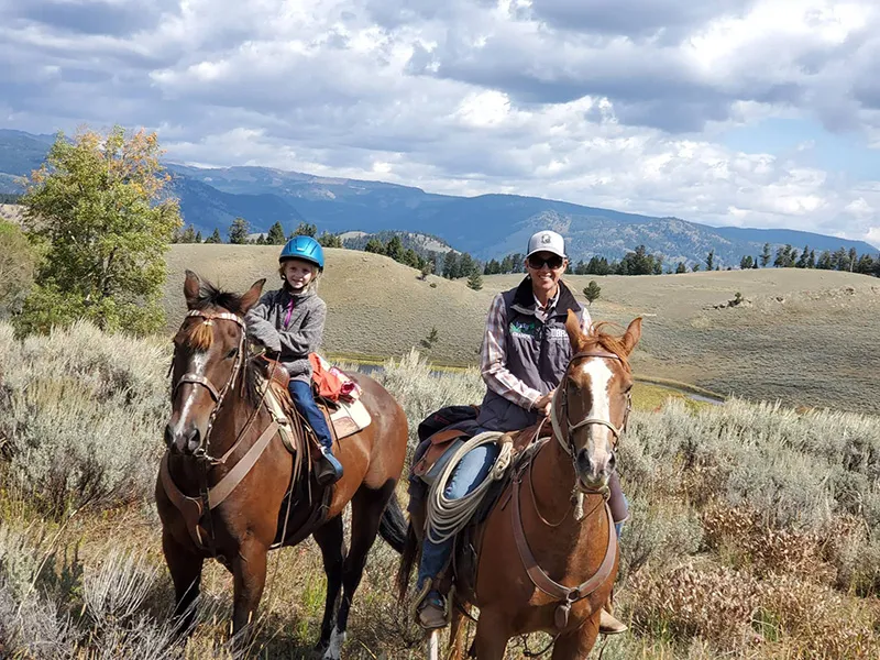 Group of horseback riders on mountain trail with scenic Yellowstone landscape views
